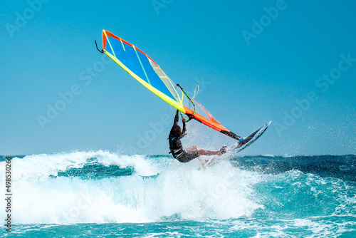 Windsurfer catching wave with board and colorful sail
