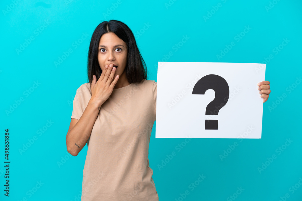 Young woman over isolated background holding a placard with question mark symbol with surprised expression Young woman over isolated background holding a placard with question mark symbol with surprised expression