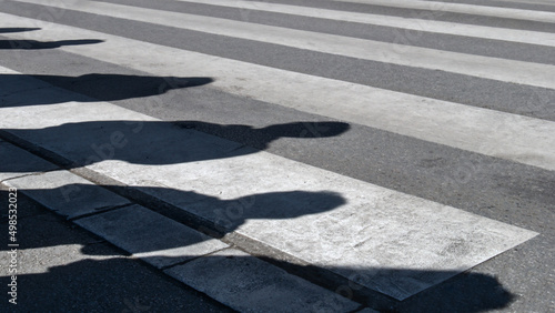 The pedestrian crossing road marks and a shadows of the people waiting to cross the street