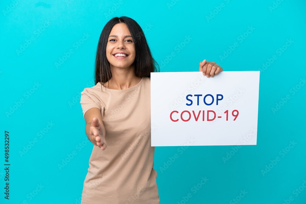 Young woman over isolated background holding a placard with text Stop Covid 19 making a deal Young woman over isolated background holding a placard with text Stop Covid 19 making a deal