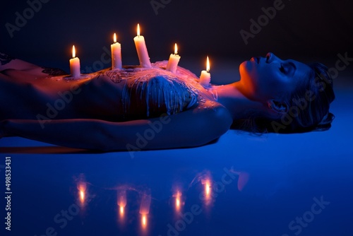 performance of laying sexy woman with burning candles on body