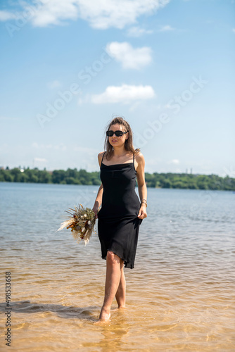 young woman stands barefoot in river