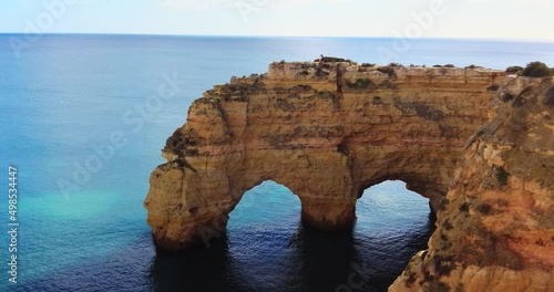 Arco Natural. A natural arch in the coast of Algarve, Portugal. Algar de benagil. Scenic afternoon view of the tourist destination, dramatic landscape. Stone Arch above the ocean.. People walking 