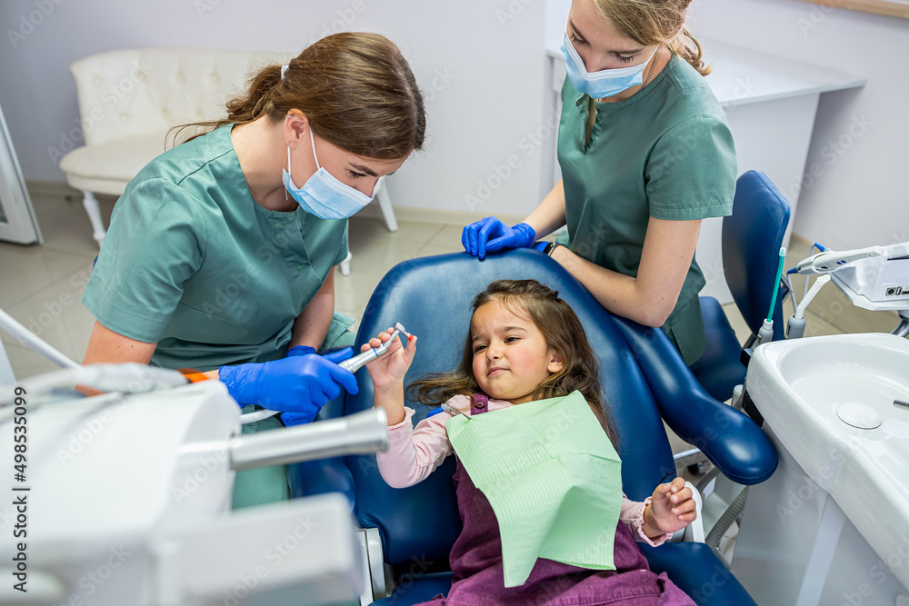 young dentist woman brushing teeth for little girl girl. young dentist woman brushing teeth for little girl girl.
