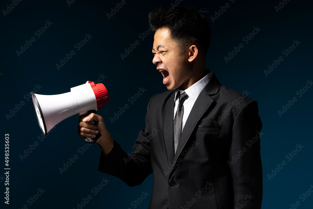 Handsome young man wearing a suit is shouting using a megaphone Handsome young man wearing a suit is shouting using a megaphone