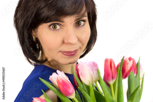 Portrait of a brunette woman with a bouquet of beautiful bright pink tulips on a white background.