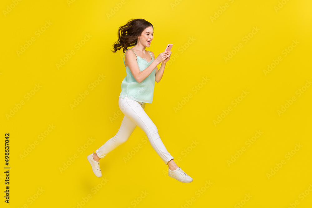 Full length profile side photo of cute charming casual wear girl surfing social media isolated on yellow color background Full length profile side photo of cute charming casual wear girl surfing social media isolated on yellow color background