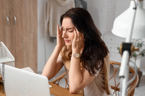 Worried young woman with laptop sitting at table