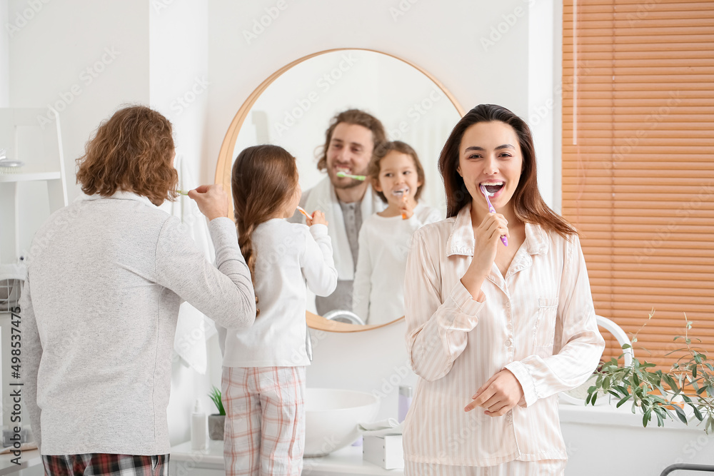 Young woman with her husband and little daughter brushing teeth in bathroom Young woman with her husband and little daughter brushing teeth in bathroom