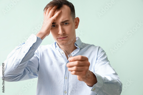 Upset young man with fallen down hair on green background