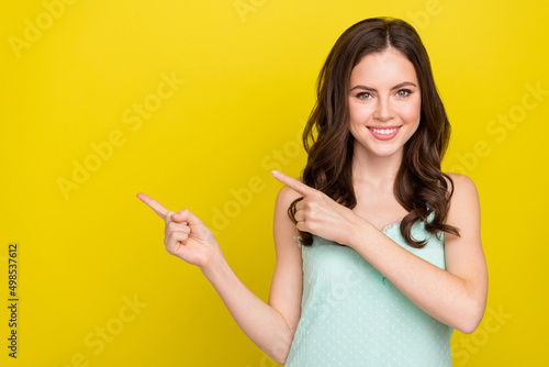 Photo of adorable positive female recommend promote offer product isolated on yellow color background