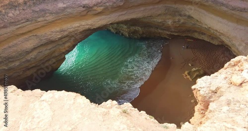 Bengali cave, no people. Ocean in the grotto. Algarve, Portugal. Bengali cave in Caroveiro. View through a hole in the ceiling above. Rock formation. Deep blue transparent ocean inside the cave.