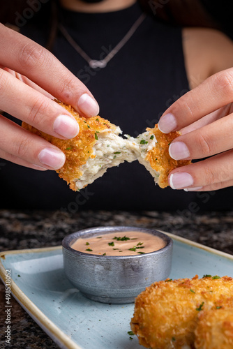 Manos de mujer cortando croqueta crujiente de pescado con salsa  photo