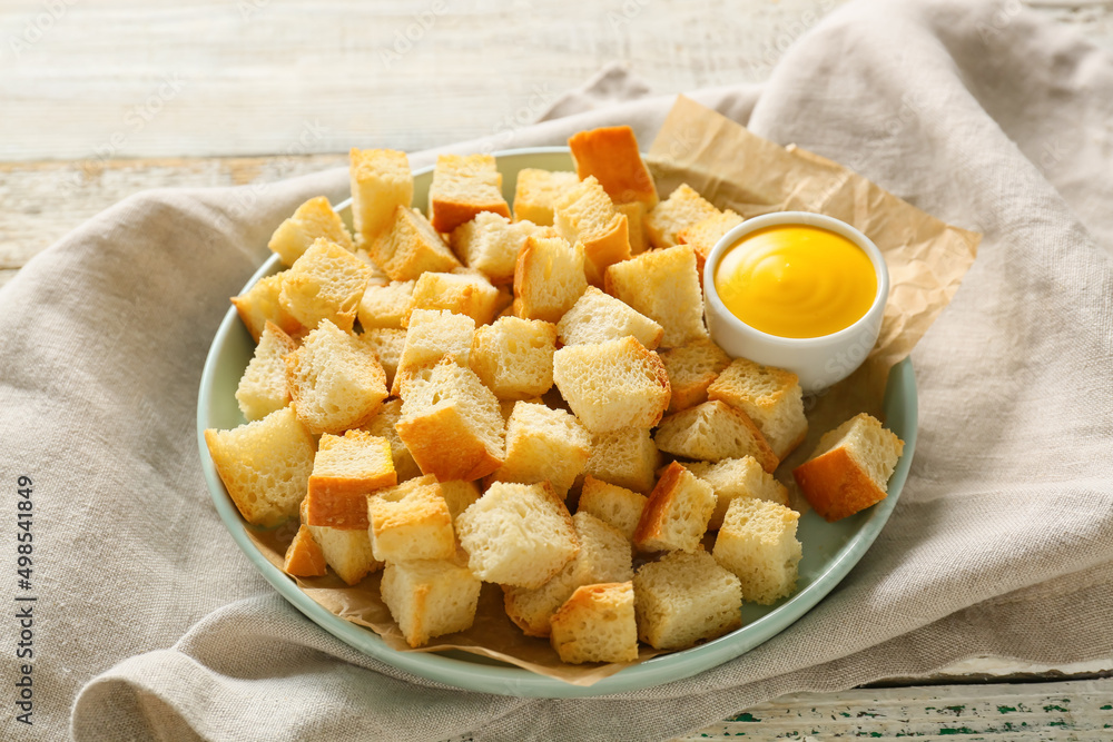 Plate of crunchy croutons and tasty sauce on wooden table Plate of crunchy croutons and tasty sauce on wooden table