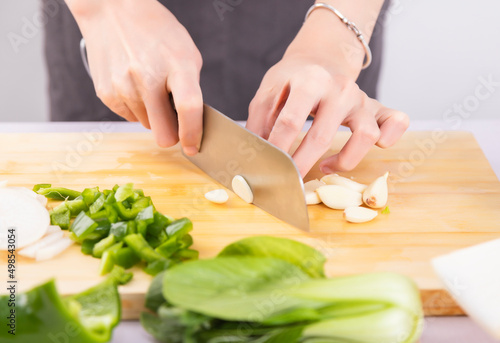 Cut vegetables on a wooden chopping board with both hands