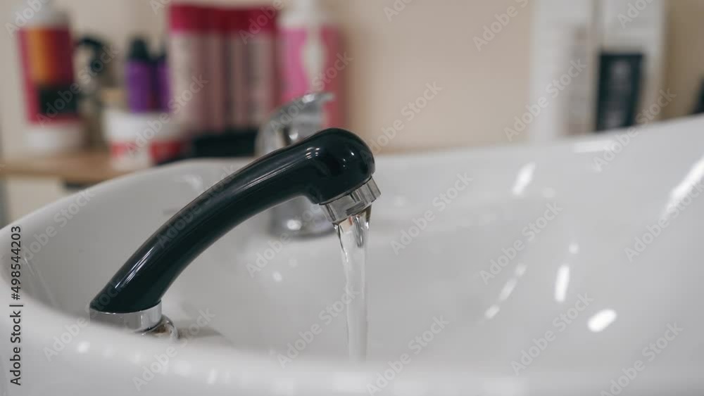 Water flows from the faucet into the washbasin Water flows from the faucet into the washbasin