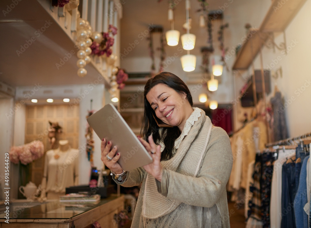 Tracking deliveries. Cropped shot of an attractive mature female entrepreneur working on a tablet in her self-owned boutique. Tracking deliveries. Cropped shot of an attractive mature female entrepreneur working on a tablet in her self-owned boutique.