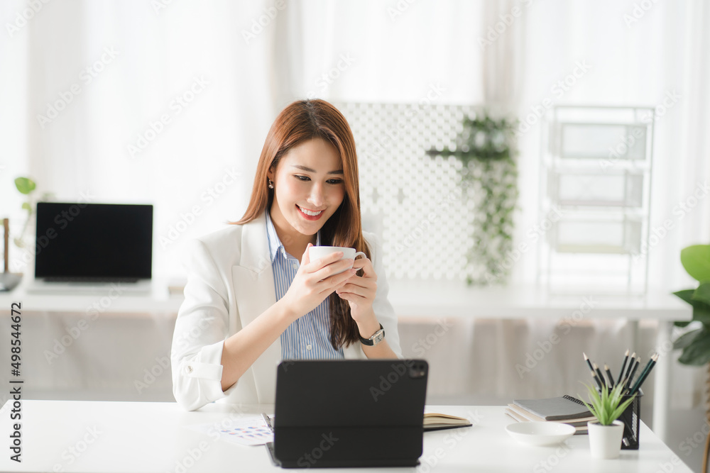 Portraits of beautiful smiling Asian women relax using laptop computer technology while sitting on their desks and using their creativity to work, work from home concept. Portraits of beautiful smiling Asian women relax using laptop computer technology while sitting on their desks and using their creativity to work, work from home concept.