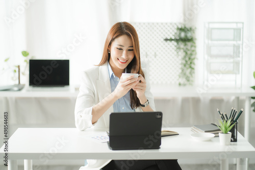 Portraits of beautiful smiling Asian women relax using laptop computer technology while sitting on their desks and using their creativity to work, work from home concept. photo