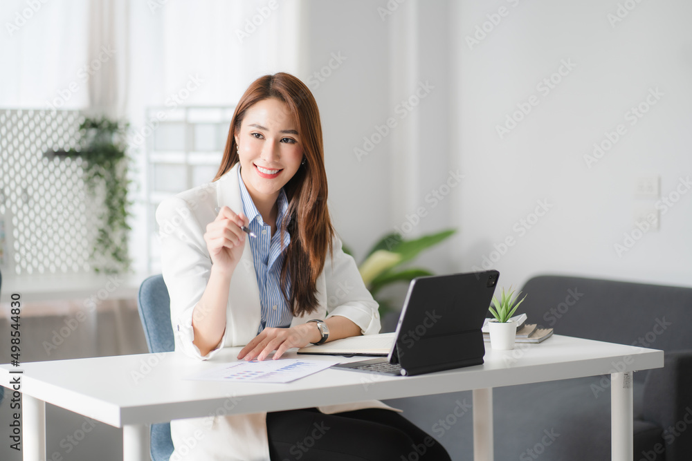 Portraits of beautiful smiling Asian women relax using laptop computer technology while sitting on their desks and using their creativity to work, work from home concept. Portraits of beautiful smiling Asian women relax using laptop computer technology while sitting on their desks and using their creativity to work, work from home concept.