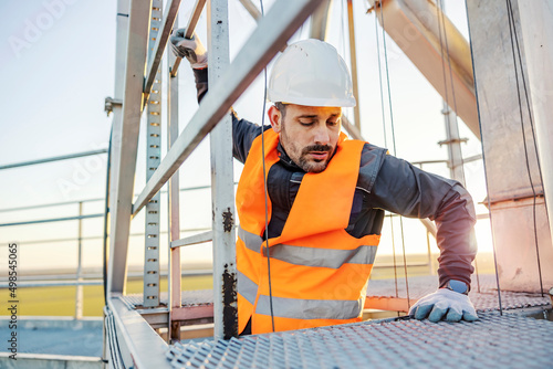 Obraz na płótnie An industry worker descending the ladders on metal construction.