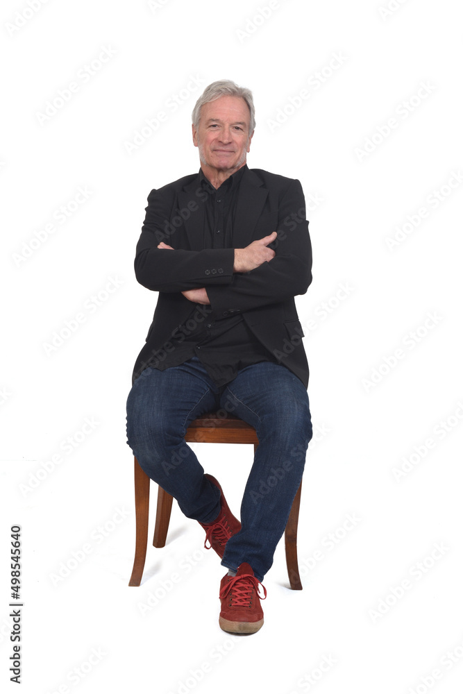 front view of a man sitting on chair with sneakers jeans and blazer, arms crossed on white background front view of a man sitting on chair with sneakers jeans and blazer, arms crossed on white background