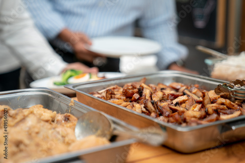 sliced fried pork in stainless rectangle plate on wood table with blur Asian office man and his dish ready to have for lunch in the background.
