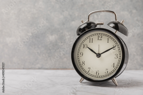 Black alarm clock on a white marble background.Time concept.