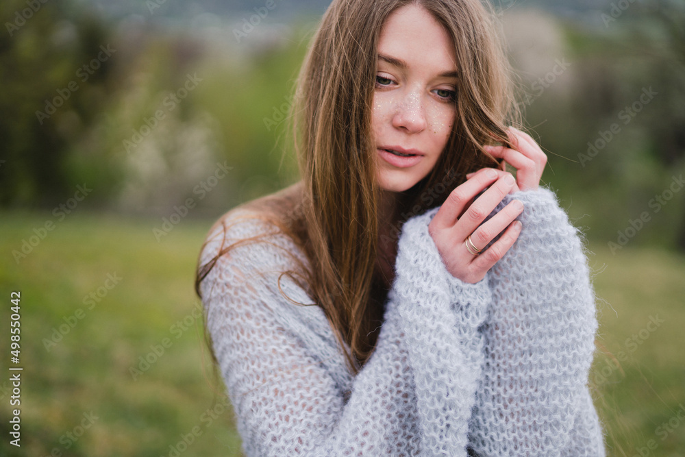 Young pretty emotional caucasian woman with long hair wearing natural makeup in romantic casual clothes walking among spring mountains near the beautiful fresh blooming tree in the countryside. Young pretty emotional caucasian woman with long hair wearing natural makeup in romantic casual clothes walking among spring mountains near the beautiful fresh blooming tree in the countryside.