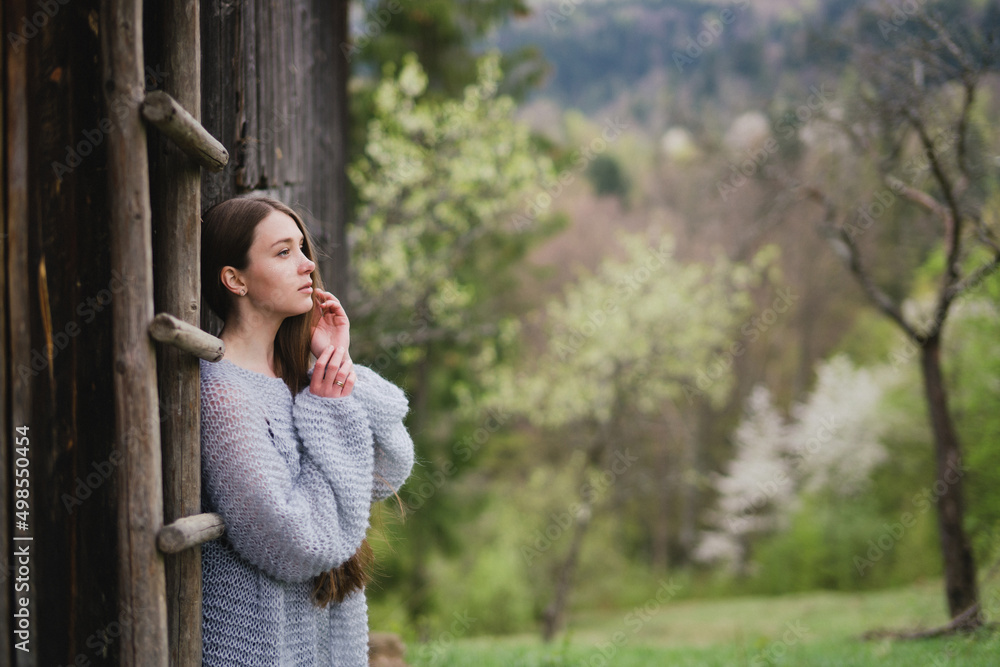Young pretty emotional caucasian woman with long hair wearing natural makeup in romantic casual clothes walking among spring mountains near the beautiful fresh blooming tree in the countryside. Young pretty emotional caucasian woman with long hair wearing natural makeup in romantic casual clothes walking among spring mountains near the beautiful fresh blooming tree in the countryside.