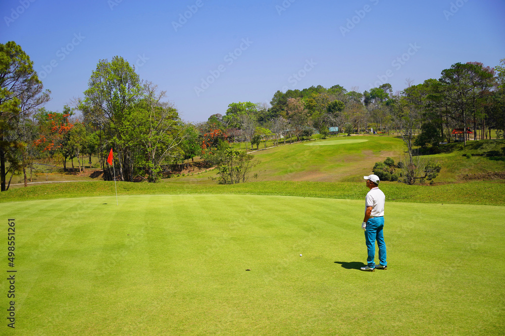 Asian golfer looking to target flag hole before swing golf. Asian golfer looking to target flag hole before swing golf.