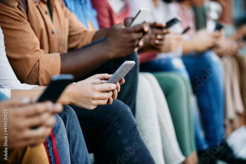 Close up of student and her university friends texting on mobile phones.