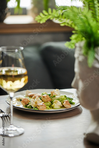 fresh appetizing salad of chicken green peas  feta cheese and cucumber on a wooden table in a restaurant