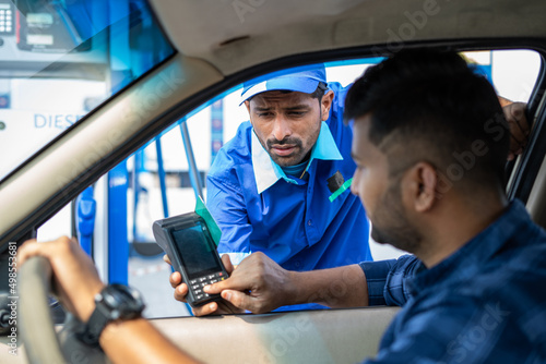 Customer paying using credit card at petrol filling station by swiping for refueling car - concept of digital casless payemt, secure transaction and banking.