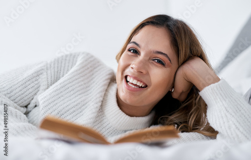 Books take me places Ive never been before. Portrait of a young woman lying on her bed with a book.