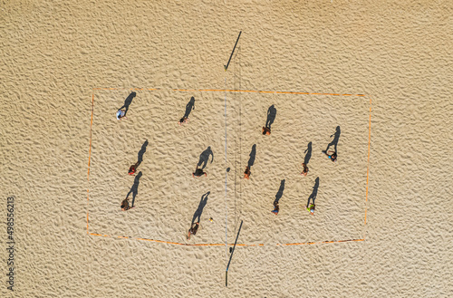 aerial footage from a drone of people playing beach volleyball on the shore. Flat view from a height of the elongated shadows of people photo