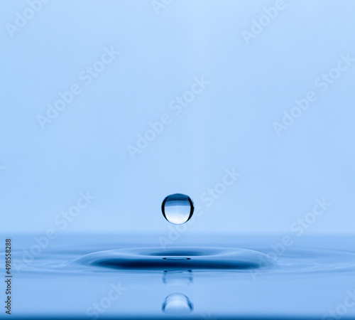 Splash and a ball of water on a blue background. Reflection on the surface of the water.