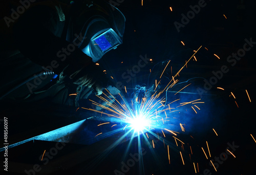 Workers wearing industrial uniforms and Welded Iron Mask at Steel welding plants, industrial safety first	
