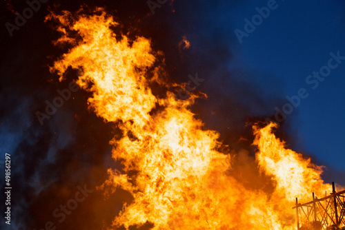 Raging flames of huge fire at night. Firestorm close up. Burning fire full frame. Bright inferno flames. Hell fire explosion. Blaze fire texture. Burning bright Bonfire. Intense combustion and heat.