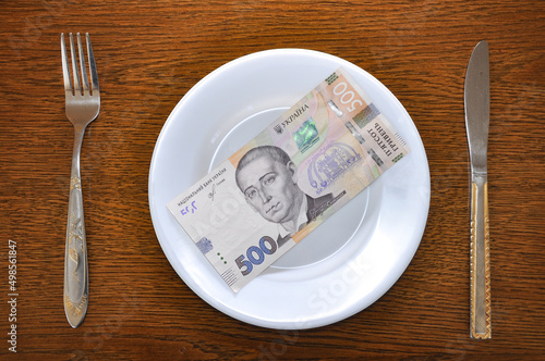 500 Ukrainian hryvnia lie on a white plate. Photo describes the problem of rising prices in the global economy