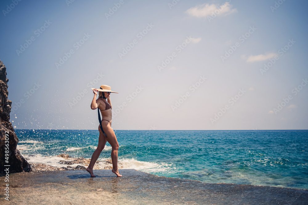 Beautiful girl blonde in swimsuit posing on the beach on the rocks Beautiful girl blonde in swimsuit posing on the beach on the rocks