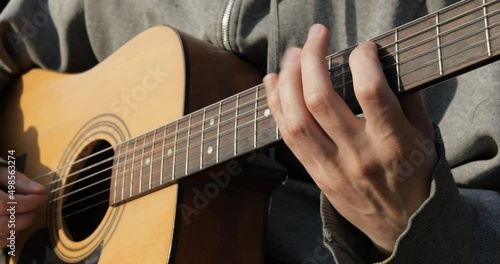 The guitarist plays the acoustic guitar close-up. Open air
