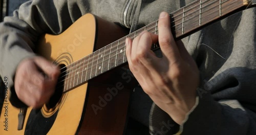 The guitarist plays the acoustic guitar close-up. Open air