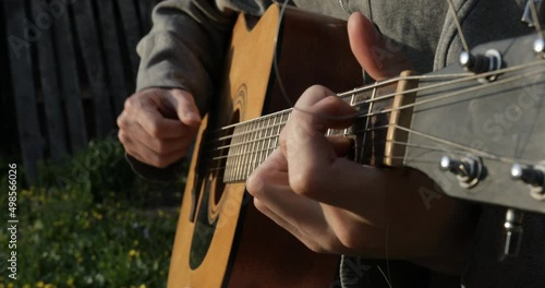 The guitarist plays the acoustic guitar close-up. Open air