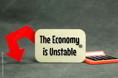 calculator, down arrow and wooden tag with the words the economy is unstable