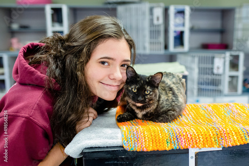 Fototapeta Brunette Teen Smiles at Camera with a Cat at a Shelter