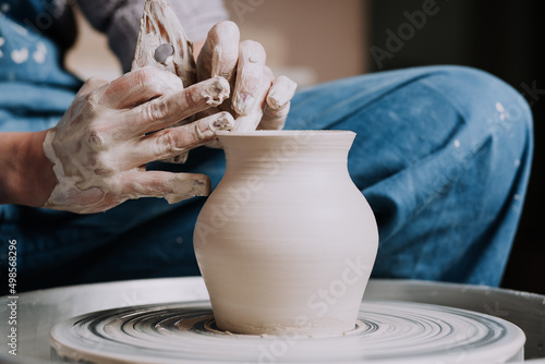 Photographie Artisan woman showing pottery vase in creative workshop