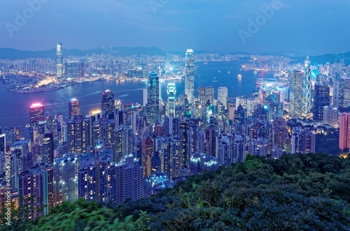 Night scenery of Hong Kong viewed from Victoria Peak with city skyline of crowded skyscrapers by Victoria Harbour and Kowloon area across seaport   Beautiful cityscape of Hong Kong in blue twilight