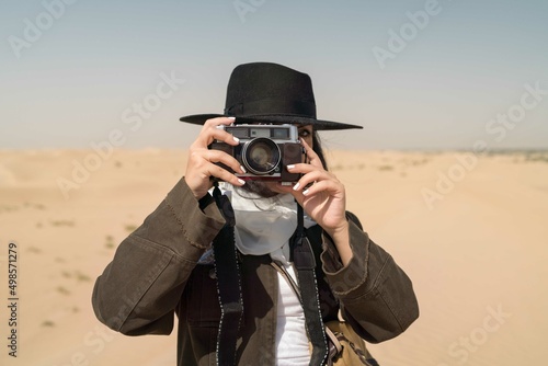 Arabic female traveler taking photos with film camera in the des photo