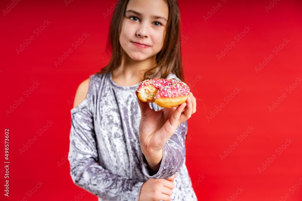 portrait of a beautiful girl in a gray dress with loose hair. teenager with donut. on a red background
